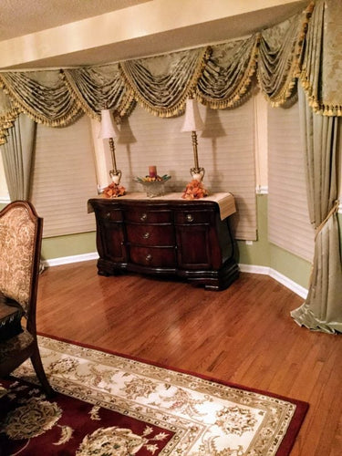 Decorative interior with ornate curtains, wooden furniture, and a patterned rug.