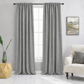 Beige curtains hanging in a living room with a couch and side table.