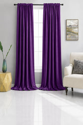 Royal Purple curtains hanging in a living room with a couch and side table.