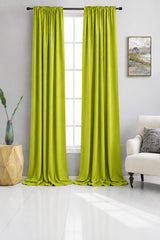 Beige curtains hanging in a living room with a couch and side table.