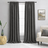 Beige curtains hanging in a living room with a couch and side table.