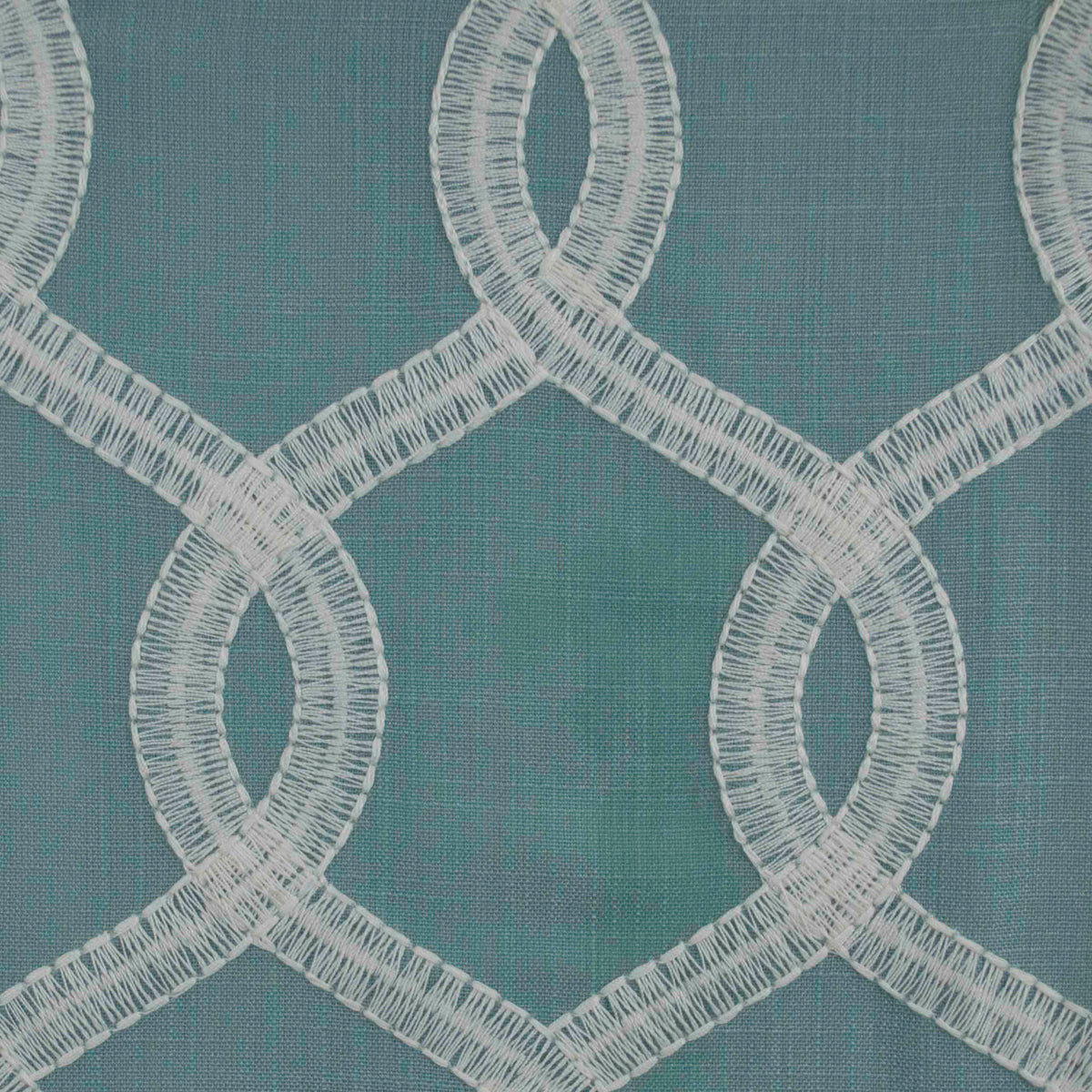 Close-up of fabric with a geometric pattern featuring blue, green, and white embroidery | Sold by Beautiful Windows Elgin